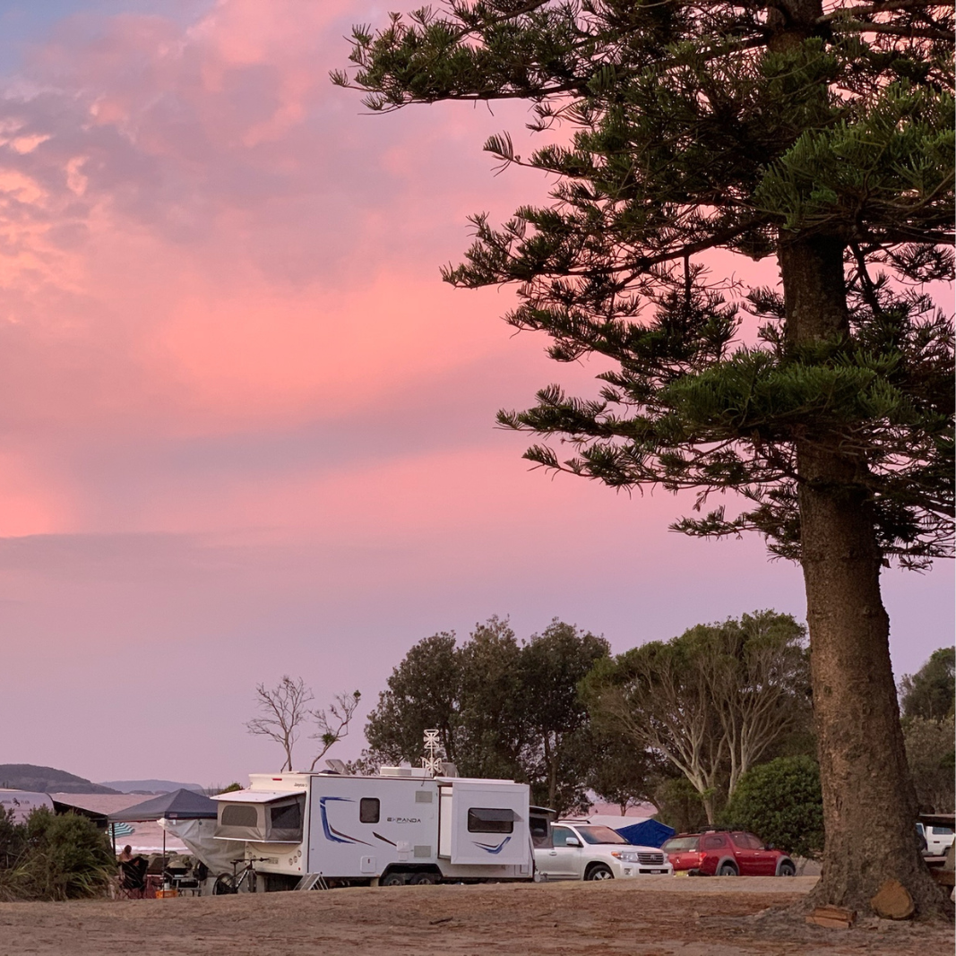 Beautiful pink and purple sky above a campground with caravans and tents